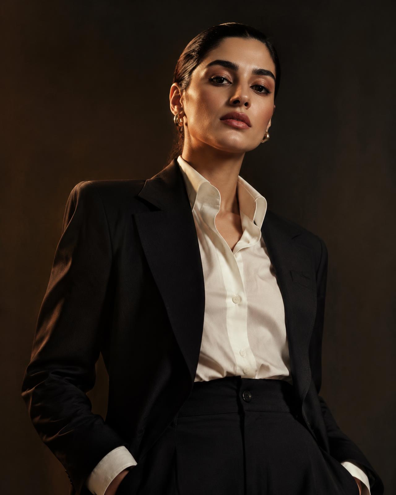 Professional in a tailored black suit and ivory shirt against a dark studio backdrop